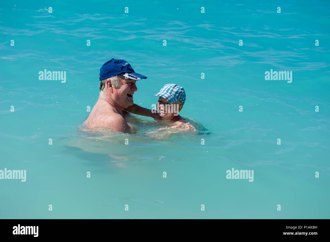 Zwei Jahre alten Sohn schwimmen mit seinem Großvater auf einem Strand, Ag. Kiriakis Strand, Kefalonia, Ionische Inseln, Griechenland, Europa Stockfoto