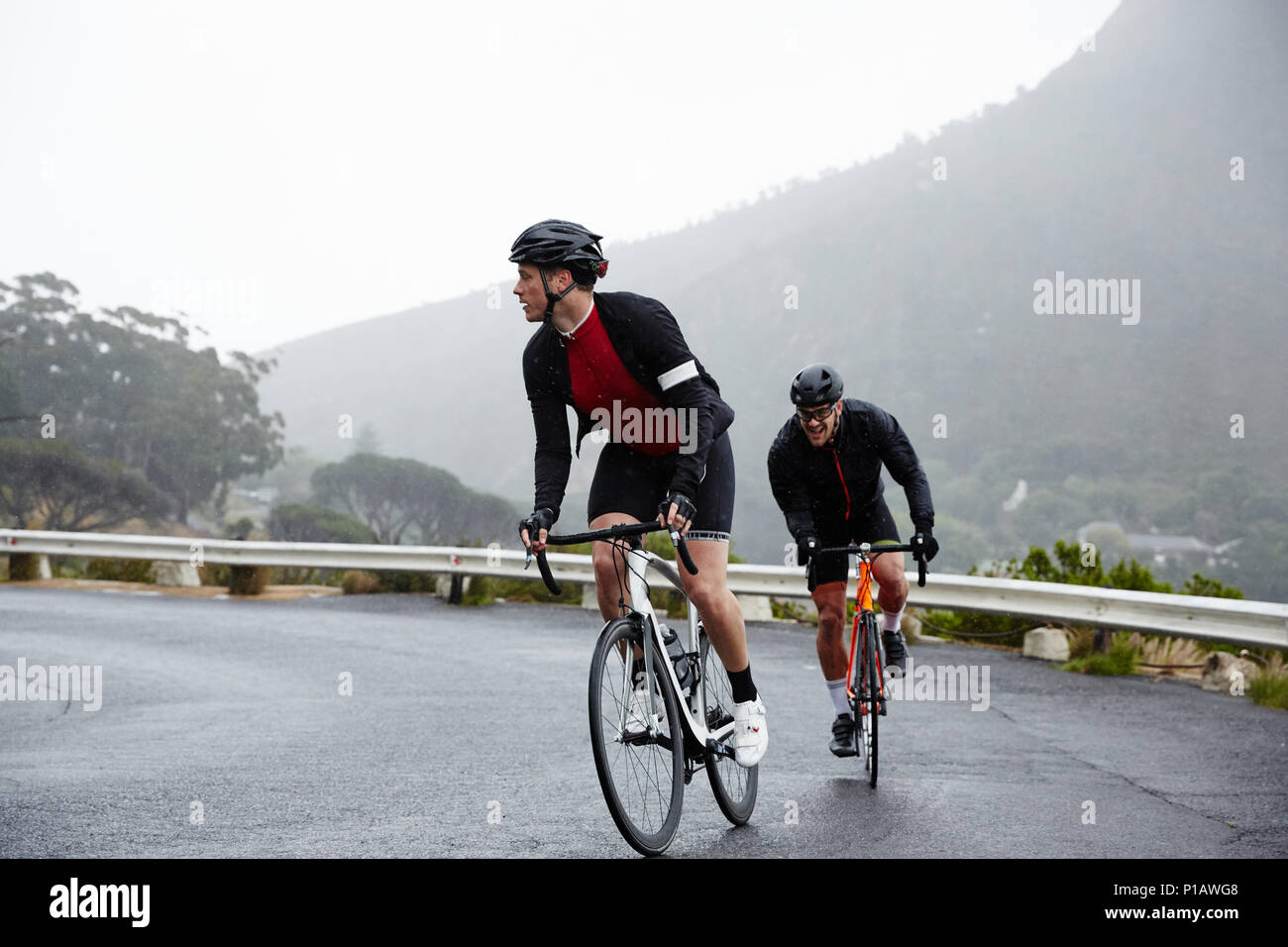 Engagierte männliche Radfahrer Radfahren auf nassen Straßen Stockfoto