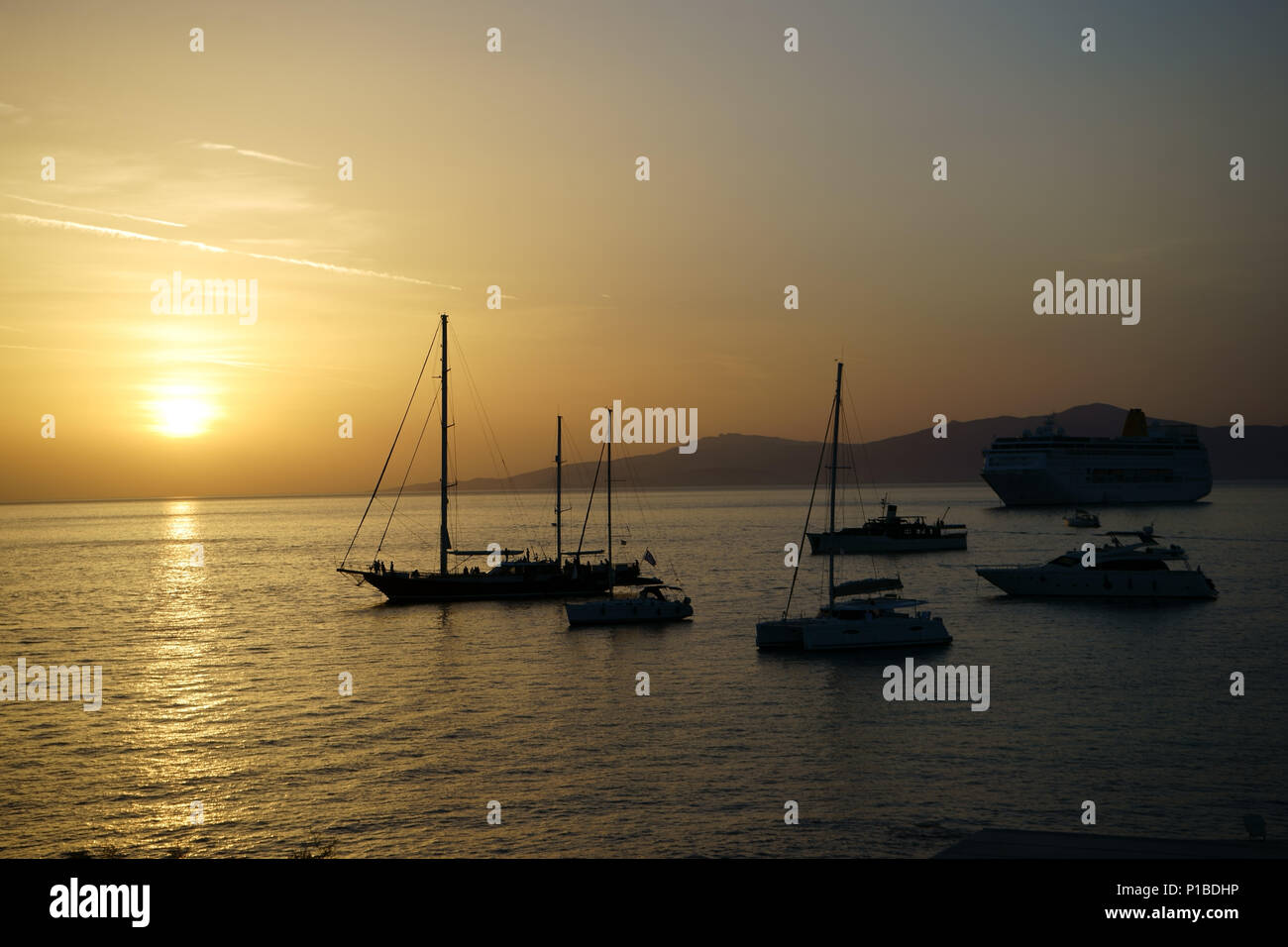 Kreuzfahrtschiff, Segel- und Motoryachten vor Mykonos bei Sonnenuntergang verankert, Insel Tinos, Kykladen, Griechenland Stockfoto