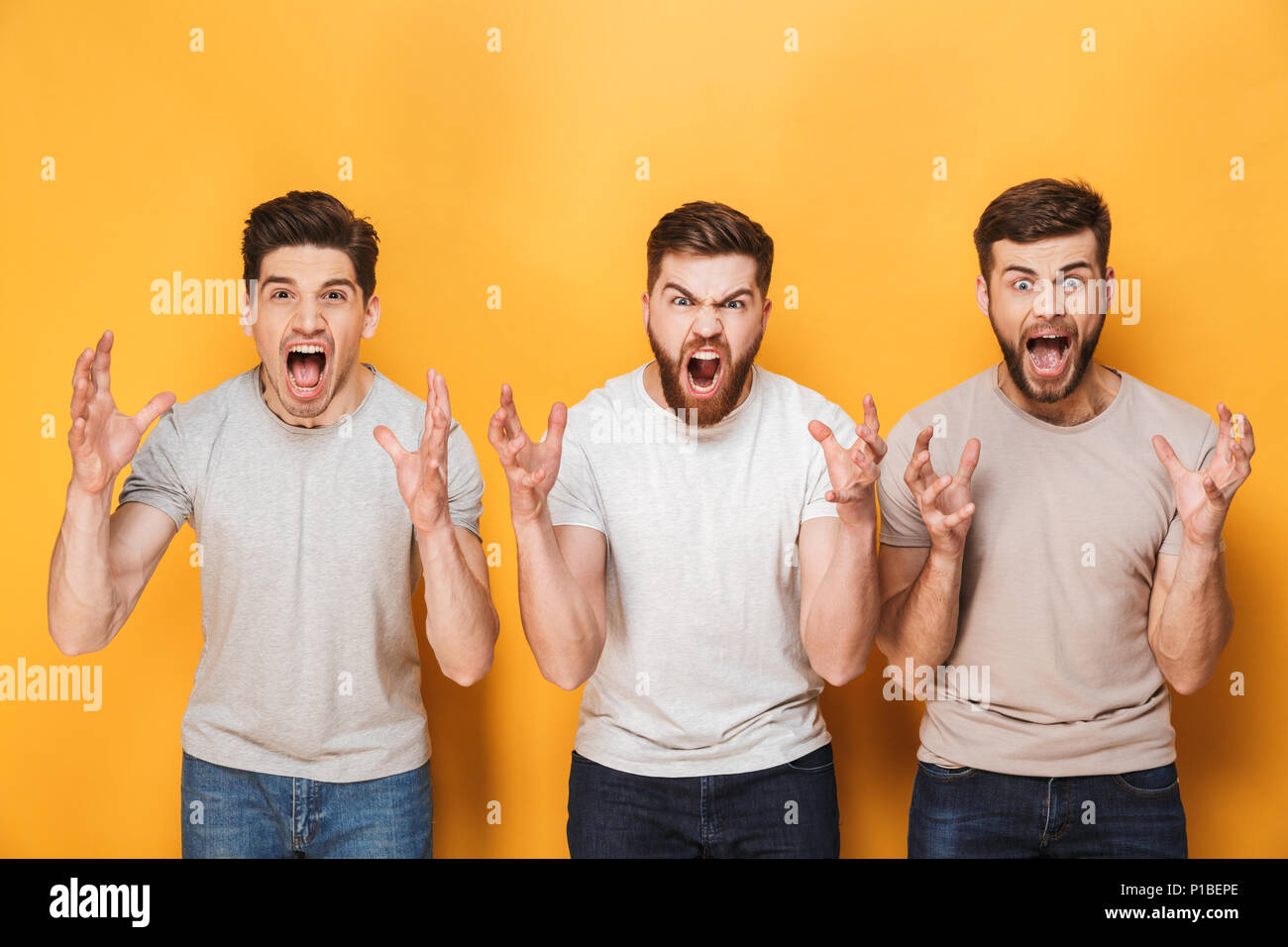 Drei junge Männer wütend Schreien über Gelb Hintergrund isoliert Stockfoto