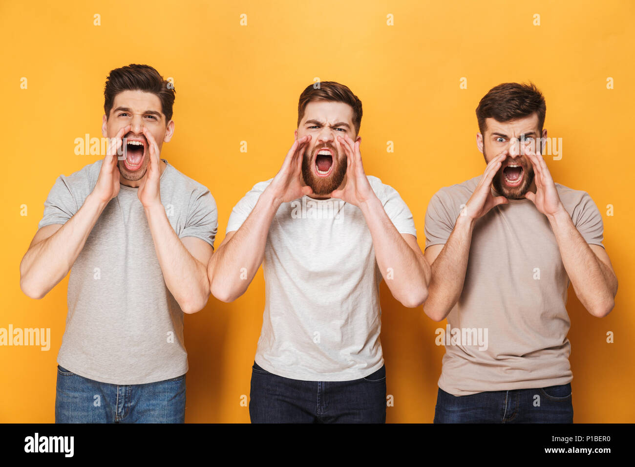 Drei junge Männer wütend Schreien über Gelb Hintergrund isoliert Stockfoto