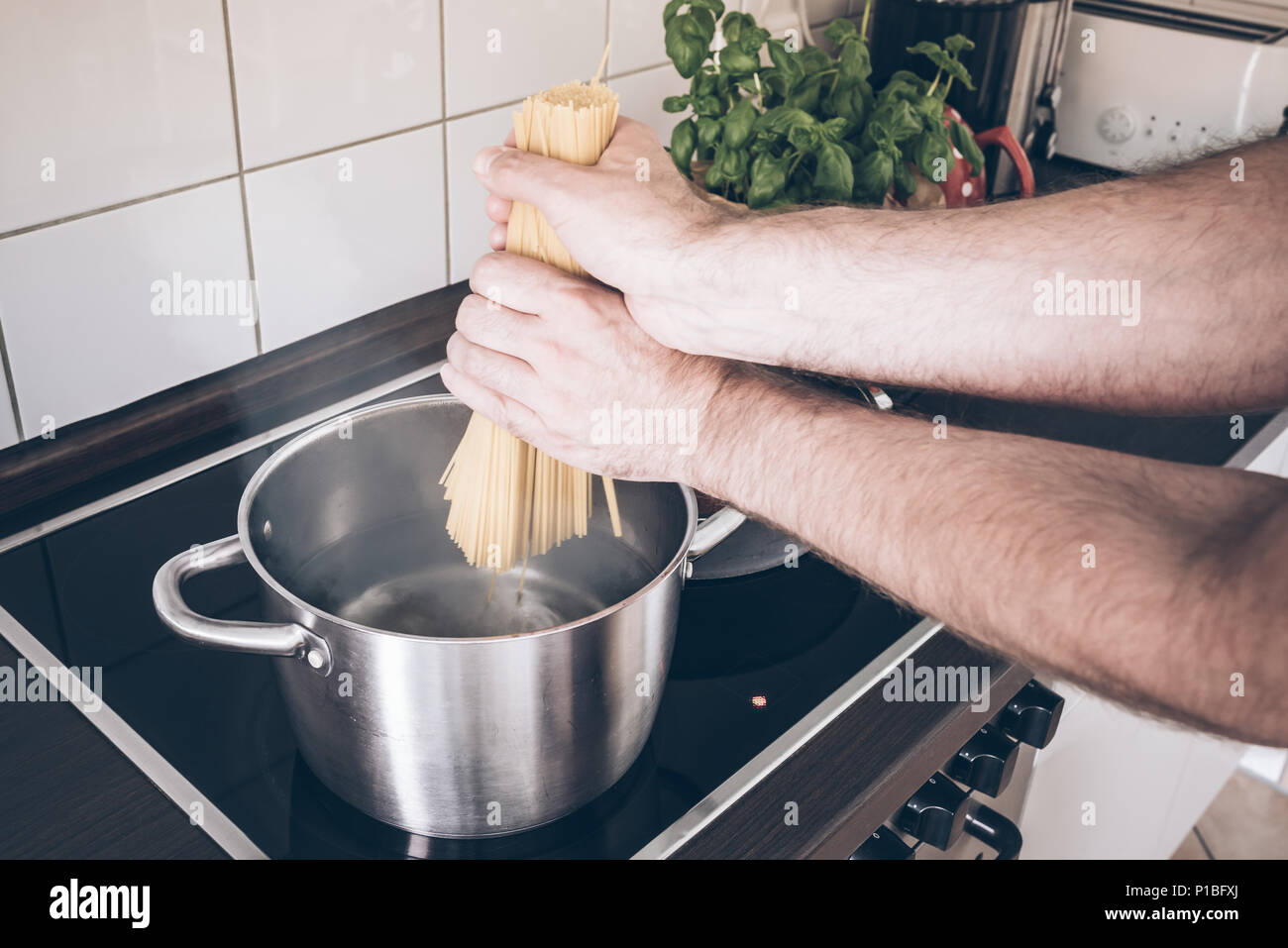 Hände, Spaghetti in den Topf mit kochendem Wasser Herd Stockfoto