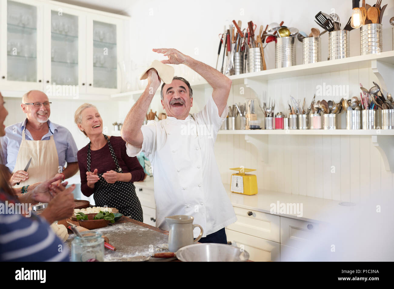 Senior friends verspielten Koch wirft Pizza Teig in Kochkurs Stockfoto