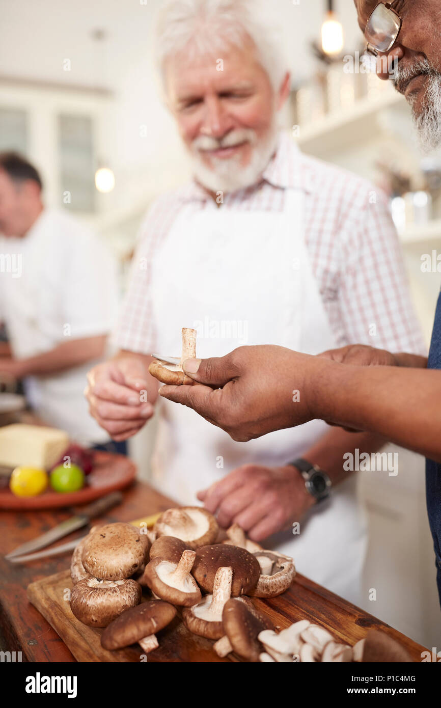 Ältere Männer Freunde schneiden frische Pilze im Kochkurs Stockfoto