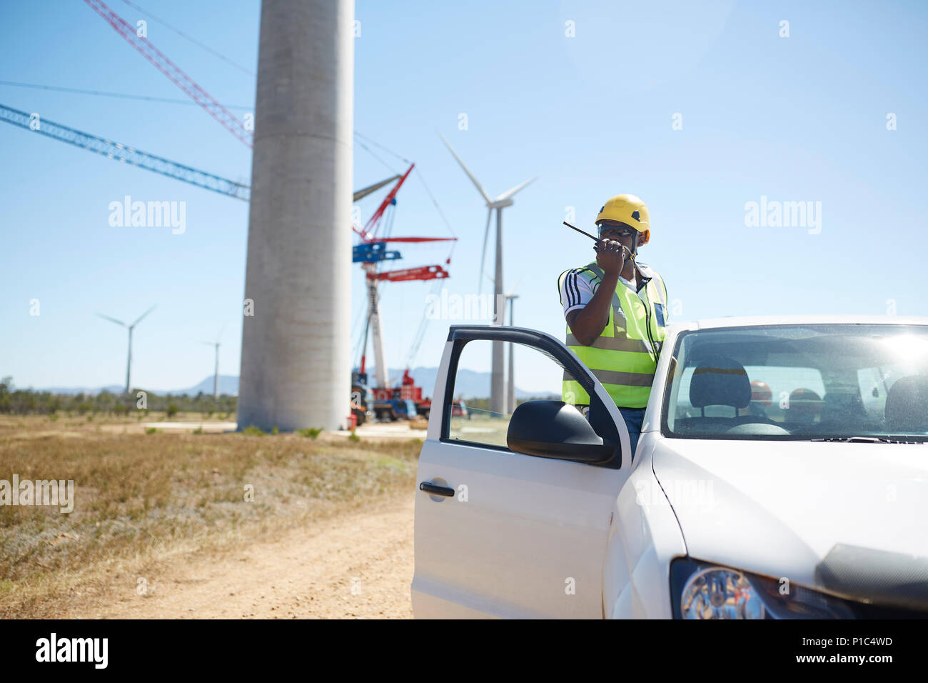Ingenieur mit walkie-talkie bei Fahrzeug bei Sunny Windenergieanlage Kraftwerk Stockfoto