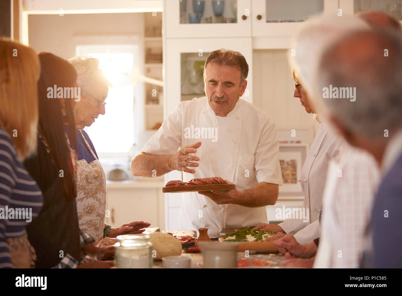 Ältere Freunde hören Chef in Pizza Kochkurs Stockfoto