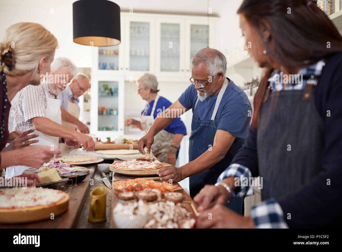 Ältere Freunde Pizzen im Kochkurs Stockfoto