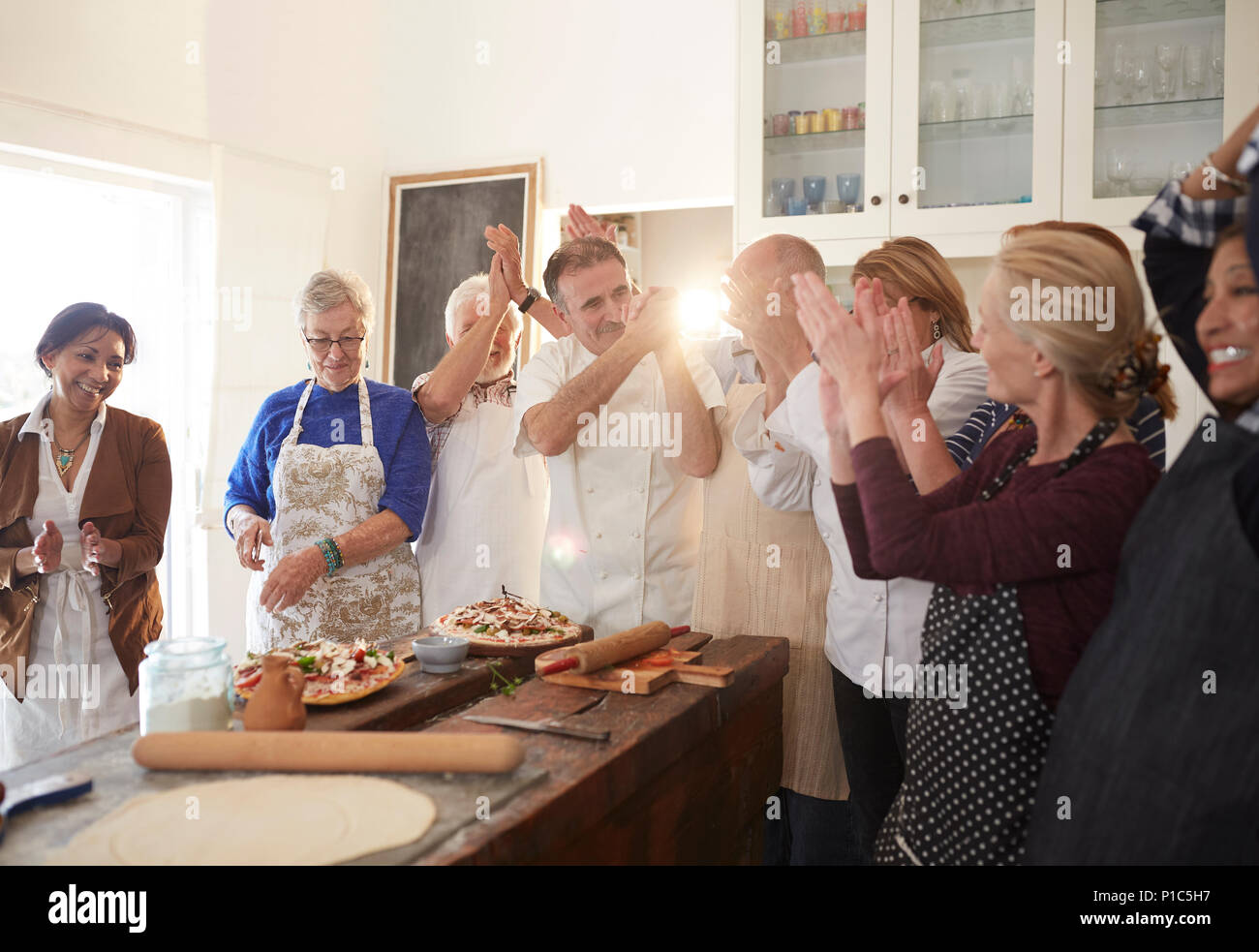 Koch und Active Senior Freunde klatschen in Pizza Kochkurs Stockfoto