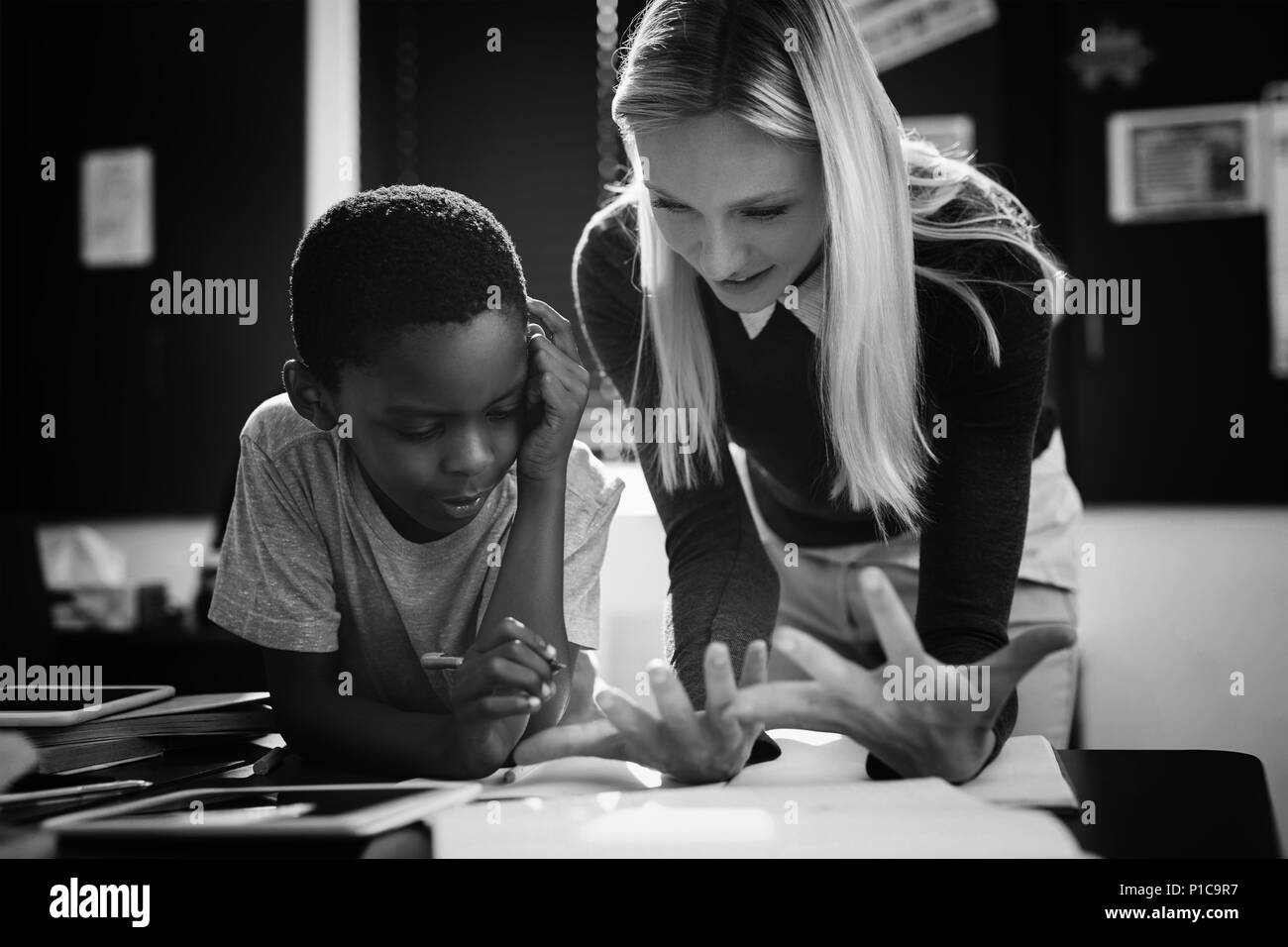 Lehrer Schulmädchen bei ihren Hausaufgaben im Klassenzimmer helfen Stockfoto
