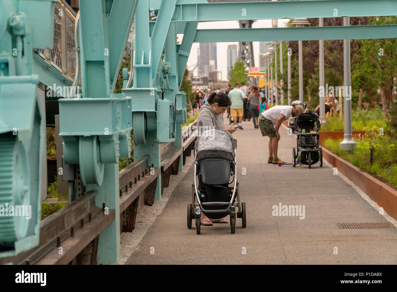 Trotz des rauhen Wetters tausende Besucher strömten zu Eröffnung von Domino Park in der Nachbarschaft von Brooklyn Williamsburg in New York am Sonntag, den 10. Juni 2018. Die Website der Domino Sugar Co. Raffinerie zu besetzen, wurde 2004 geschlossen, die fünf Hektar großen greenspace hat Wasser, Rutschen, einen erhöhten Laufsteg, Danny Meyer Essen stehen und Volleyball sowie viele andere Annehmlichkeiten. Von James Corner Field Operations konzipiert, die Architekten hinter dem Design der High Line, der Backstein Raffinerie Gebäude, die gleichzeitig 50 Prozent aller Zucker in den USA verarbeitet bleibt für de Stockfoto