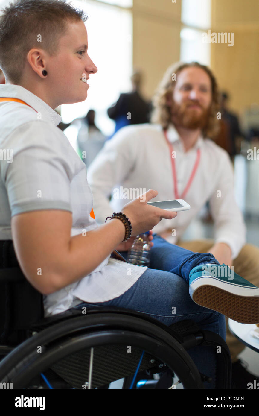Frau im Rollstuhl mit smart phone bei der Konferenz Stockfoto
