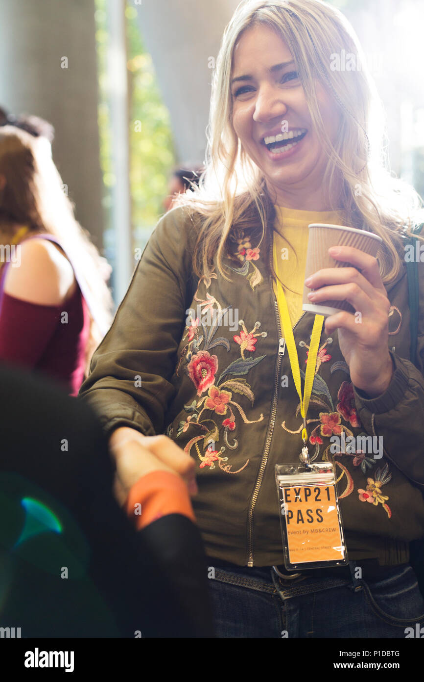 Lächelnde Frau mit Kaffee bei der Konferenz Stockfoto