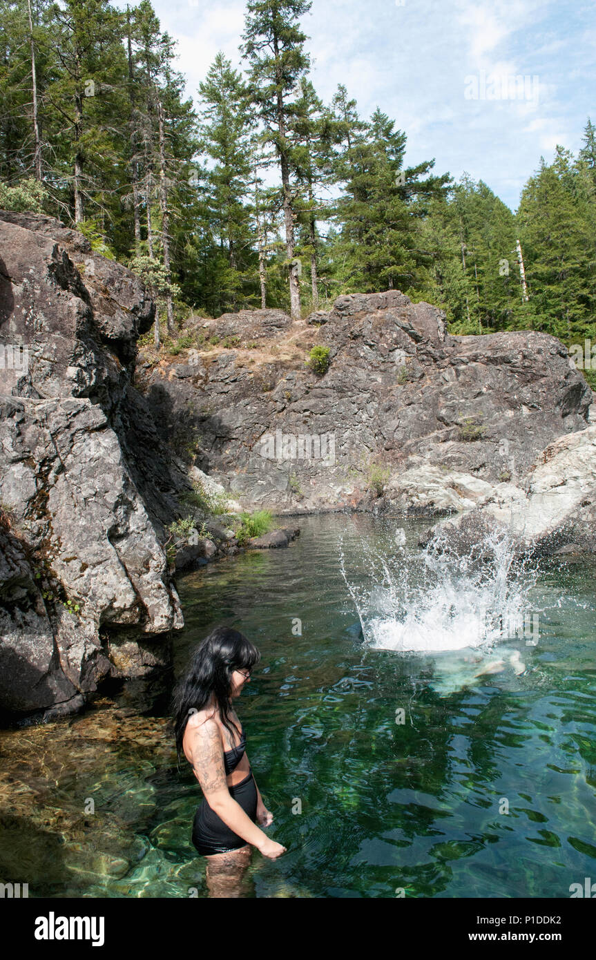 Eine Frau ein Mann springt aus einem Felsen bei Opal Creek Wilderness Area, drei Pools schwimmen Löcher, Oregon Stockfoto