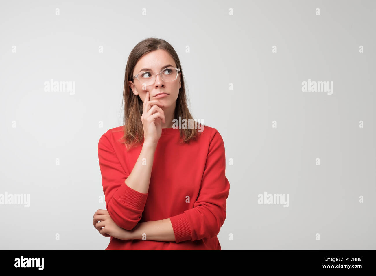 Nachdenklich europäische Frau in Rot Pullover ist auf der Suche bis zu denken oder zu planen. Stockfoto