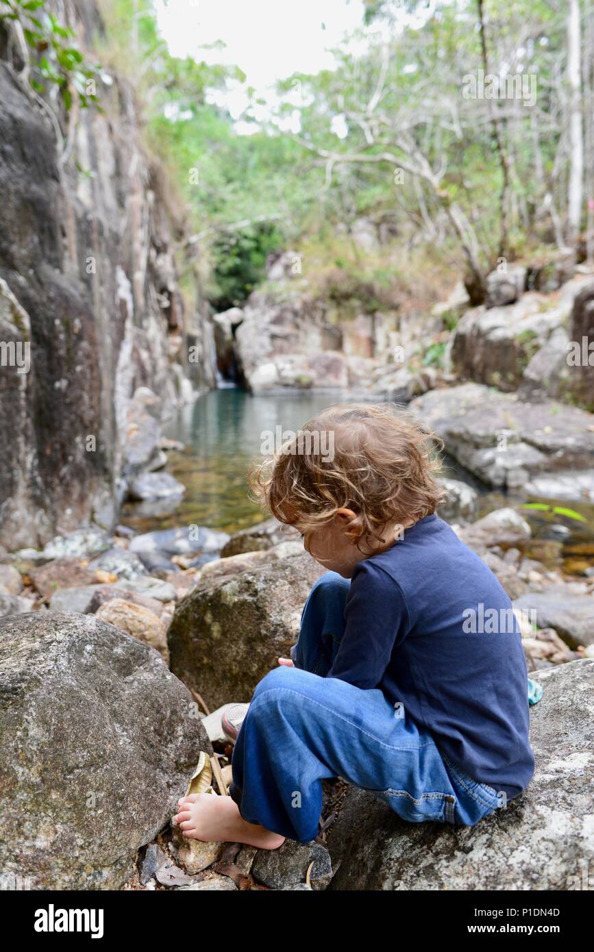 Junge Mädchen setzen auf ihre Socken und Schuhe in einer natürlichen Umgebung, Paluma Range National Park, Rollingstone QLD, Australia Stockfoto