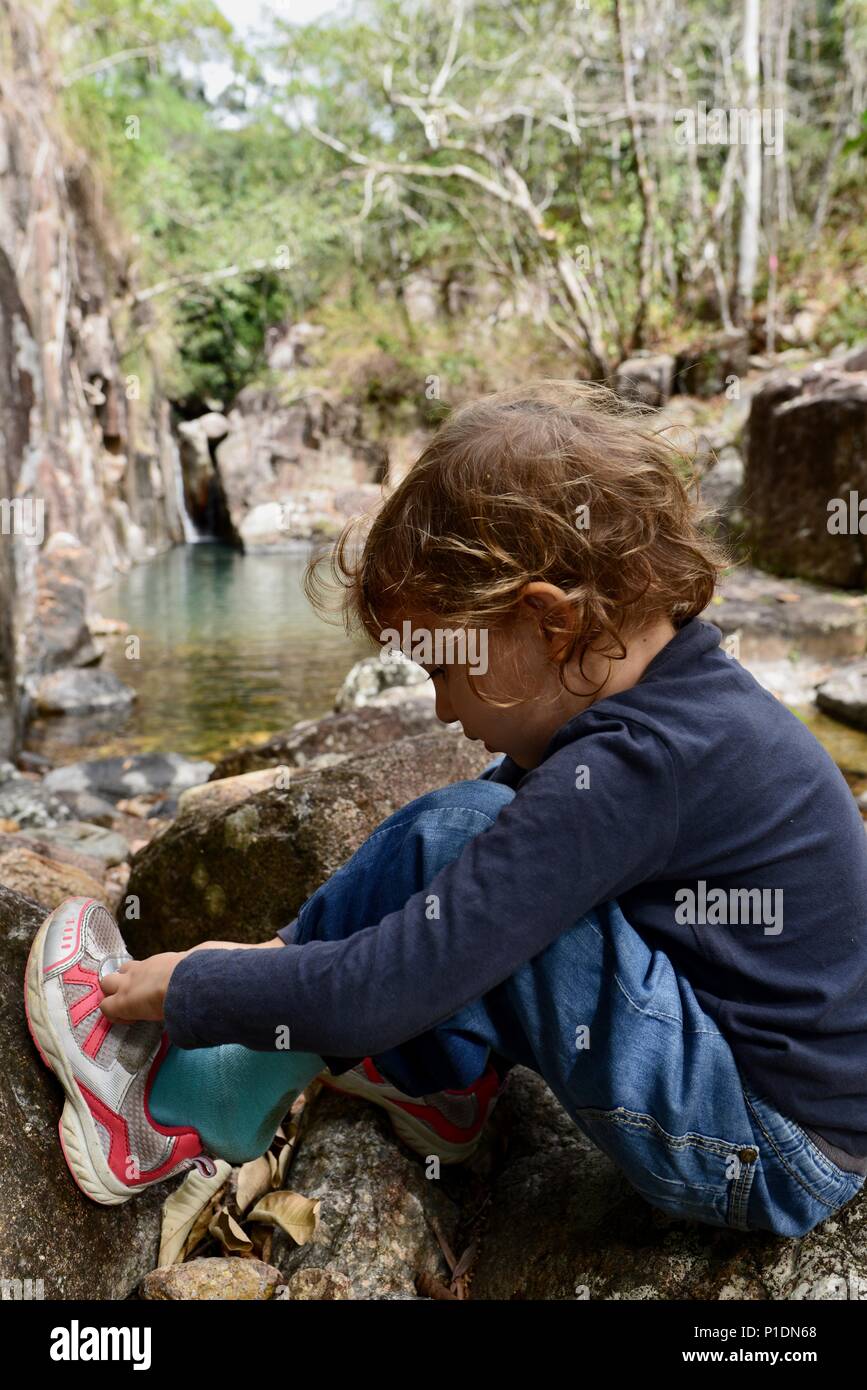 Junge Mädchen setzen auf ihre Socken und Schuhe in einer natürlichen Umgebung, Paluma Range National Park, Rollingstone QLD, Australia Stockfoto