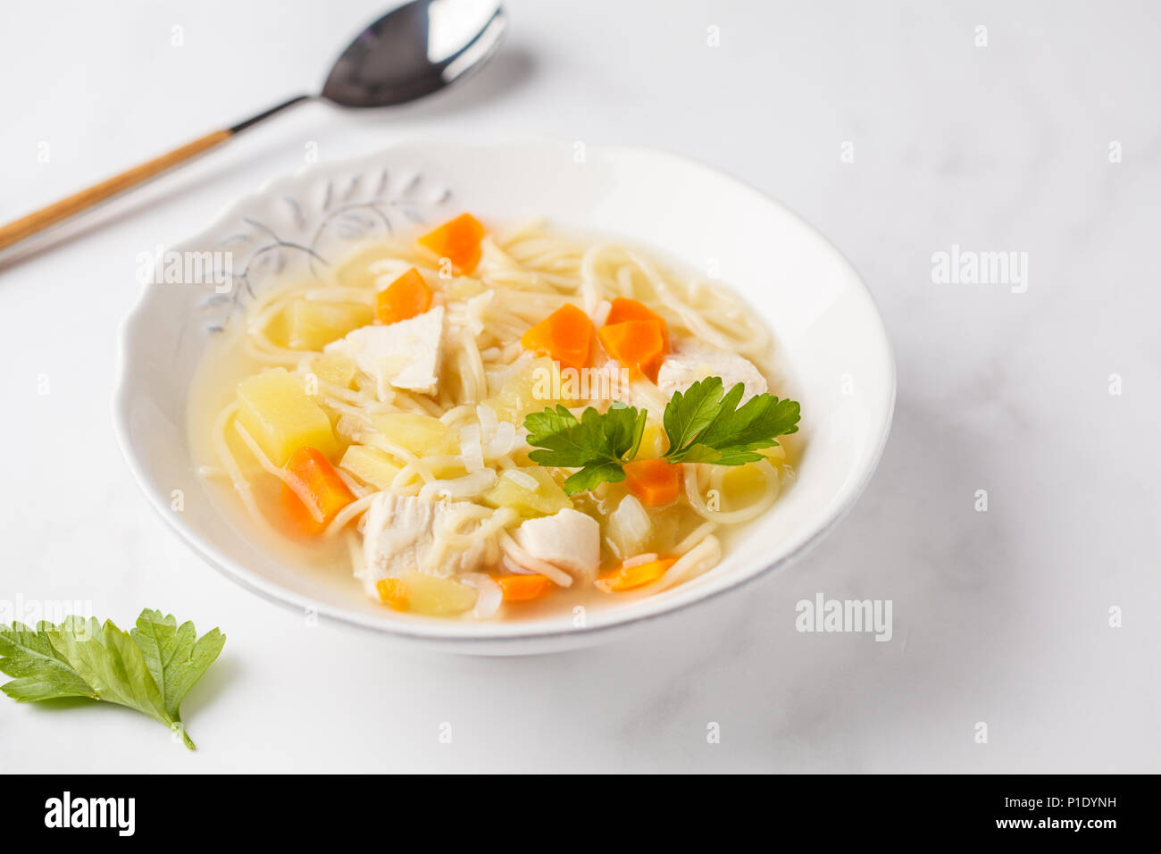 Hühnersuppe mit Nudeln und Gemüse in eine weiße Platte, weisser Hintergrund. Stockfoto