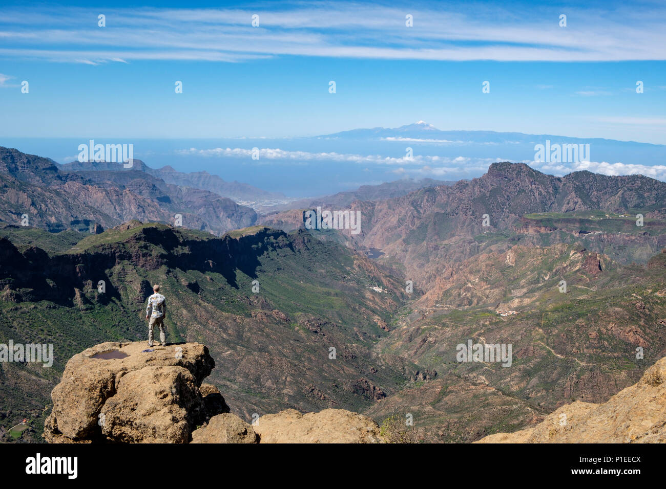 Mann sieht von Roque Nublo über die bergige Land von Gran Canaria auf den Vulkan Teide, Gran Canaria, Kanarische Inseln, Spanien Stockfoto