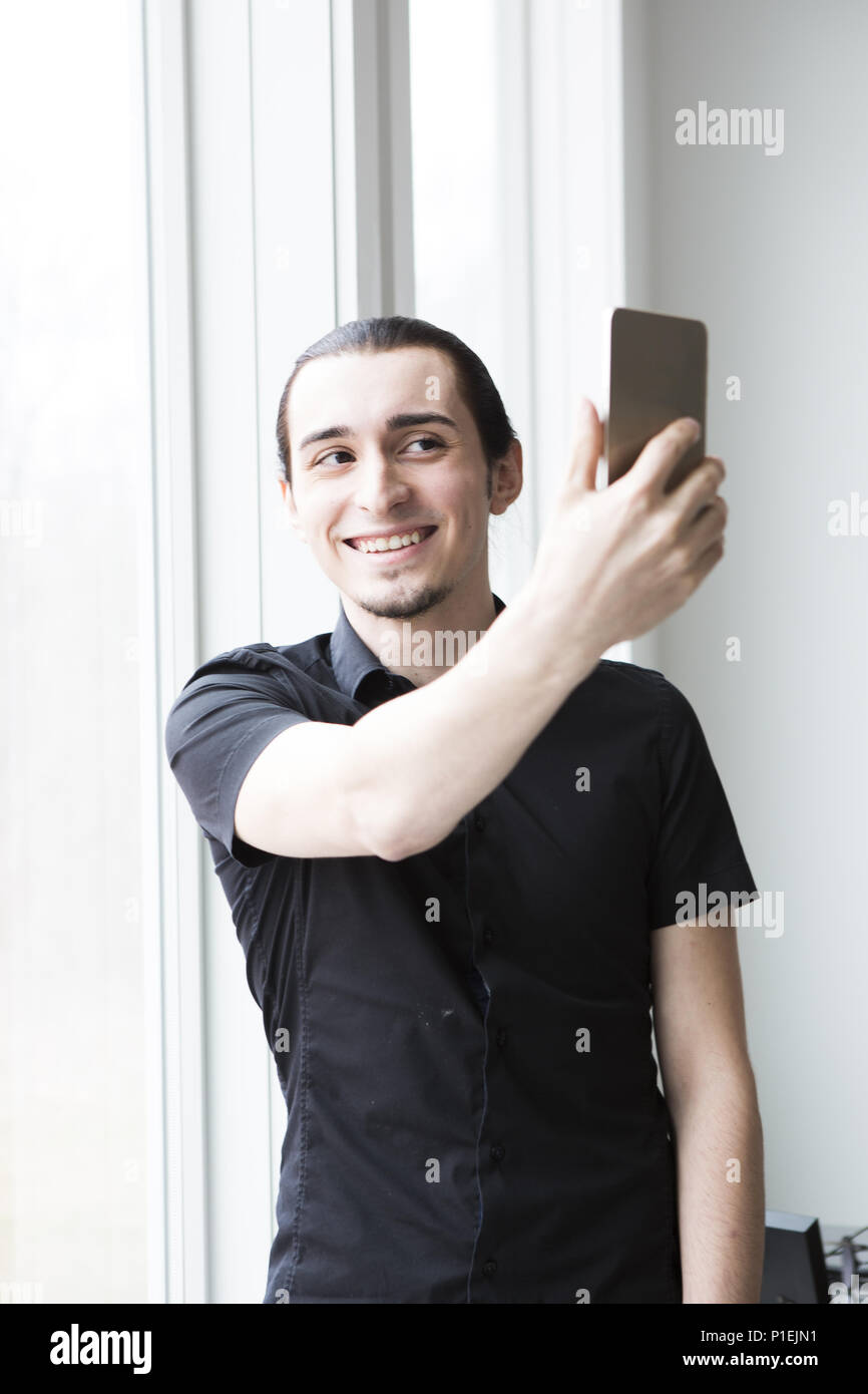 Ein junger Geschäftsmann, ein Foto mit einem Handy in einem modernen Büro. Stockfoto