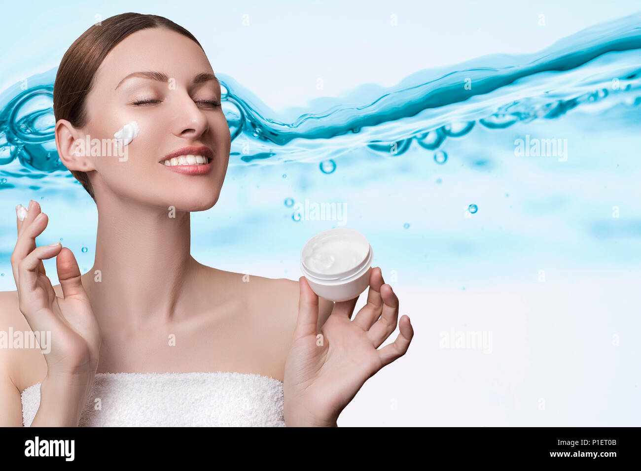 Schönes Modell Spa Frau mit Spritzwasser. Schöne lächelnde Mädchen unter Wasser mit frischen Haut über blauen Hintergrund. Hautpflege, reinigt Stockfoto