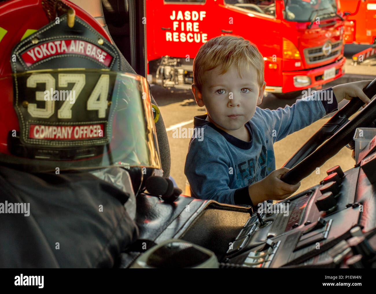 Während der Brandverhütungswoche auf dem Yokota Air Base, Japan, nahmen Kinder an interaktiven Aktivitäten teil, darunter Posen in einem Feuerwehrauto im Yokota Community Center. Bei der Veranstaltung wurden Feuerwehrausrüstung der 374th Civil Engineer Squadron, der japanischen Luftwaffe Fire and Rescue und der Tokio Fire Department gezeigt. Das Programm förderte das Bewusstsein für die Brandsicherheit, die Aufklärung über Notfallmaßnahmen und das Engagement mit kommunalen und militärischen Mitarbeitern. Stockfoto