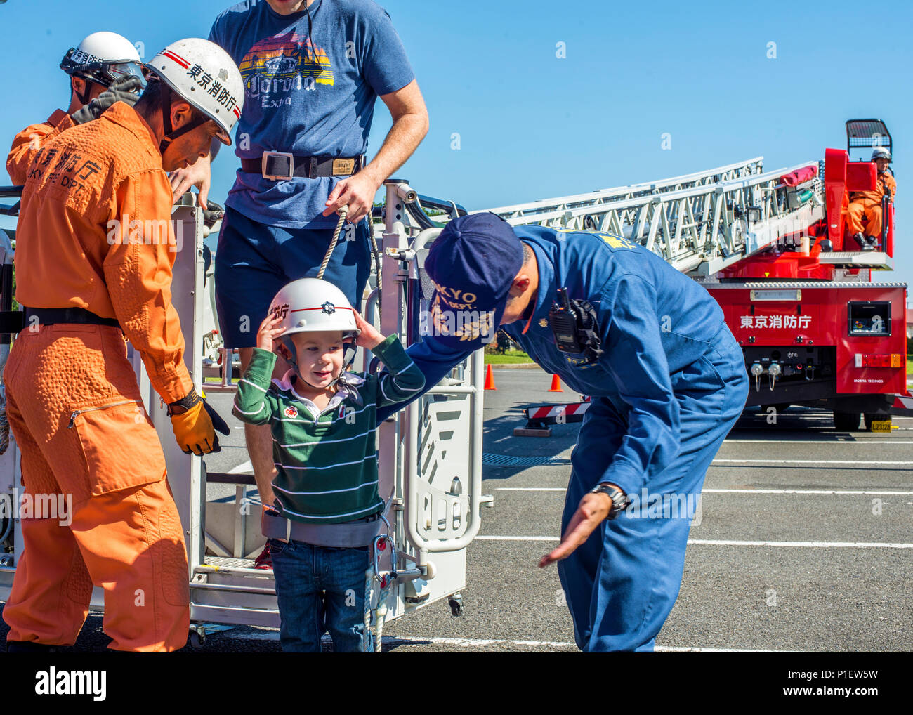 Auf der Yokota Air Base, Japan, wurden Kinder während der Fire Prevention Week von einer ausfahrbaren Leiter eines Feuerwehrwagens im Community Center begleitet. Bei der Veranstaltung wurden Feuerwehrausrüstung der 374th Civil Engineer Squadron, der japanischen Luftwaffe Fire and Rescue und der Tokio Fire Department gezeigt. Die Aktivitäten konzentrierten sich auf Brandschutz-Aufklärungen, Notfallverfahren, praktische Demonstrationen und das Engagement der Gemeinschaft für Kinder und Militärangehörige. Stockfoto