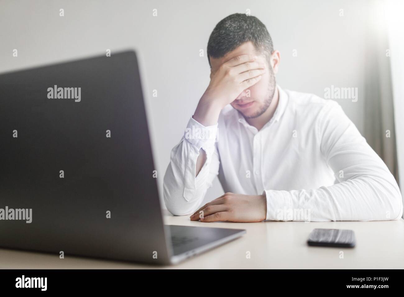 Junge lächelnde bärtigen Geschäftsmann arbeitet auf dem Computer Holding Stockfoto