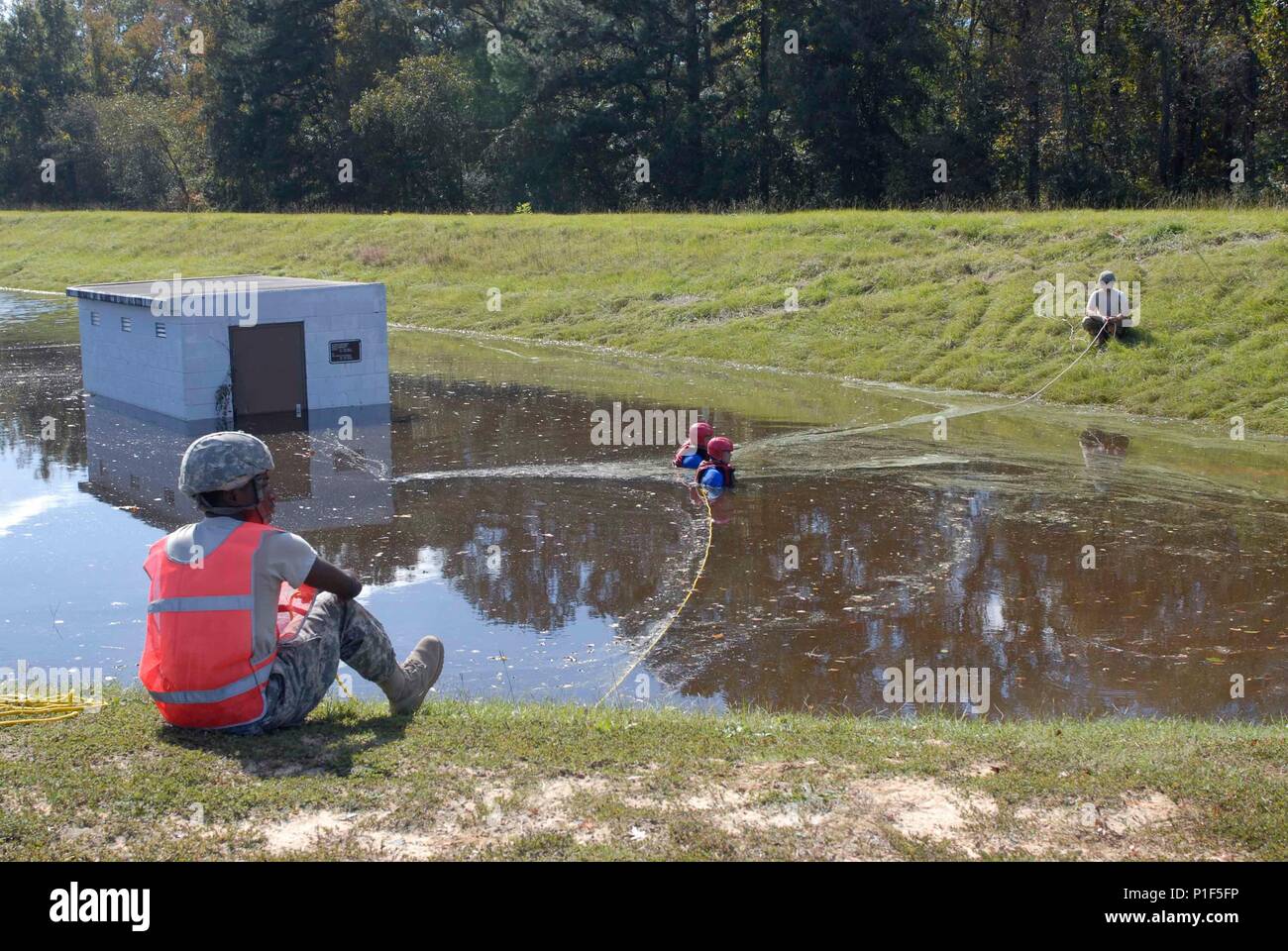 TARBORO, N.C. - North Carolina Army National Guard Soldaten, der 130 Manöver Verbesserung Brigade, die verhindern, dass Wasser pumpe Siebe hier von Verschmutzung, indem Sie sie ersetzen oder Hinzufügen von neuen Pumpen, 16. Okt. 2016. Sgt. Jack McDonald und Sgt. William Cayton-LED auf der Vorderseite, wie sie auf dem nassen Anzüge statt Multitasking, um den Job zu Untergebenen. Die beiden standen im Hochwasser für die meisten des Tages. Wenn die Gruppe am Standort angekommen, das Wasser war so hoch wie die kleinen braunen Schild auf dem Gebäude. Obwohl die Stadt noch unter ungefähr 8 Fuß Wasser ist, die Soldaten sind bereit, die Arbeit zu tun, bis die Arbeit tun Stockfoto