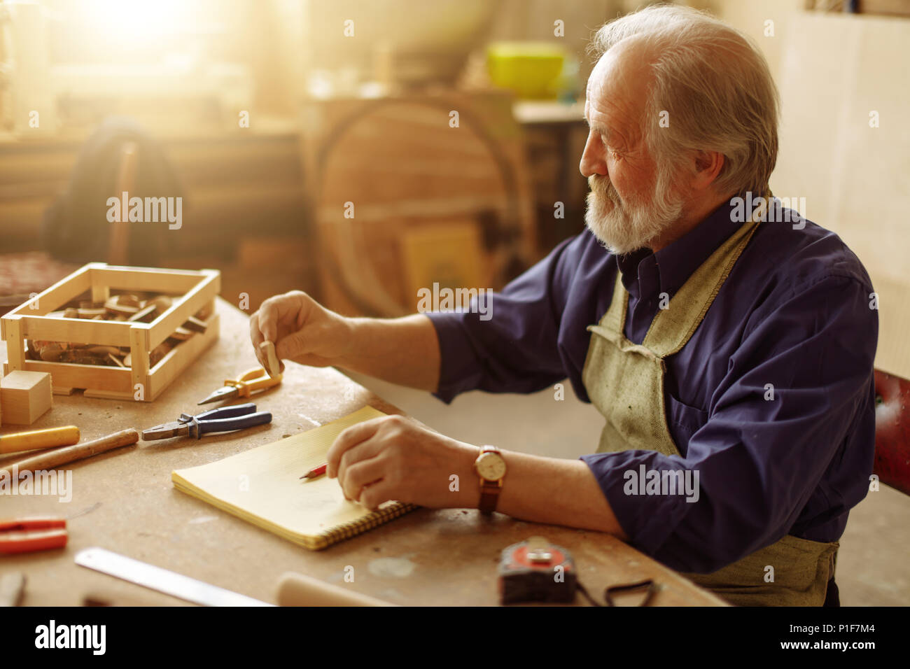 Alter Mann mit grauen Haaren, Souvenir aus Querschnitt von Baum zu machen Stockfoto
