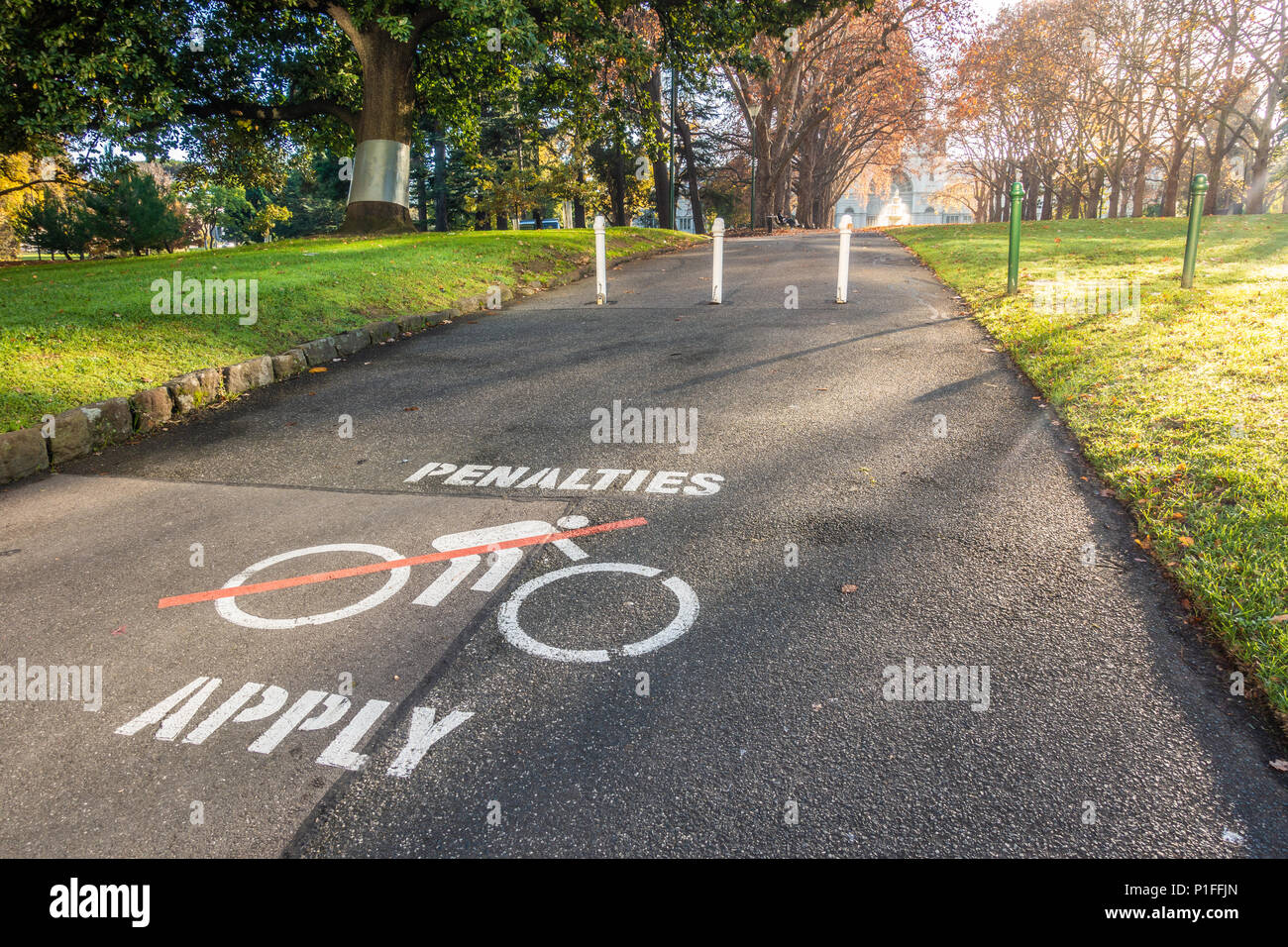 "Sanktionen" Warnschild Malerei auf dem Asphalt Fußweg Radfahrer zu erinnern, in der öffentliche Garten zu demontieren. Melbourne, VIC, Australien Stockfoto