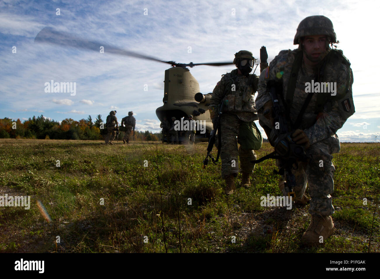 Ein Soldat von 94Th Military Police Firma zieht Sicherheit, während andere eine CH-47 Chinook aus der B-Company, 3-10 Allgemeine Unterstützung Aviation Battalion, am Fort Drum, NY Last, am 23. Oktober. Das Training war Teil des 10 Mountain Division jährlichen Gipfel (LI) die Übung und befasste sich mit der Steuerung eines Riot und helfen verletzte Zivilisten. (U.S. Armee Foto von SPC. Thomas Scaggs) Foto 7/8, Licht und Farbe in Photoshop 161023-A-TZ 475-576 ausgeglichen Stockfoto