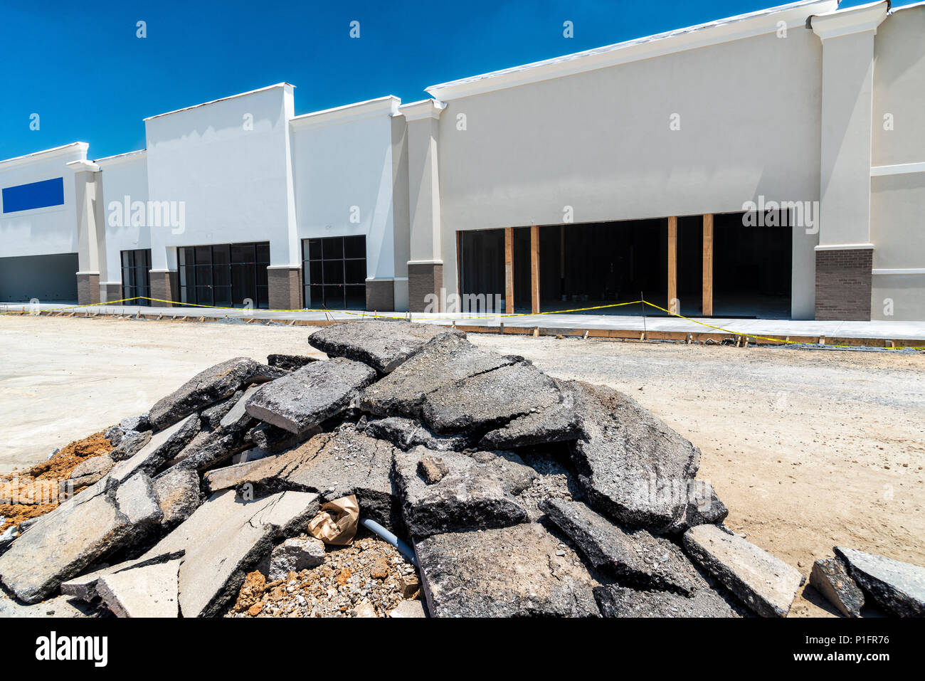 Neubau eines neuen Retail Strip Shopping Center. Große Datei von zerrissen Zahlung im Vordergrund. Stockfoto