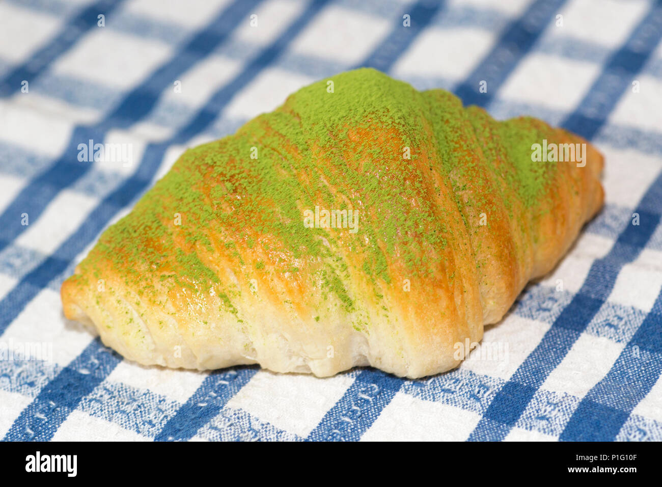 Frisches Matcha-Croissant auf einem blau karierten Tuch Stockfoto