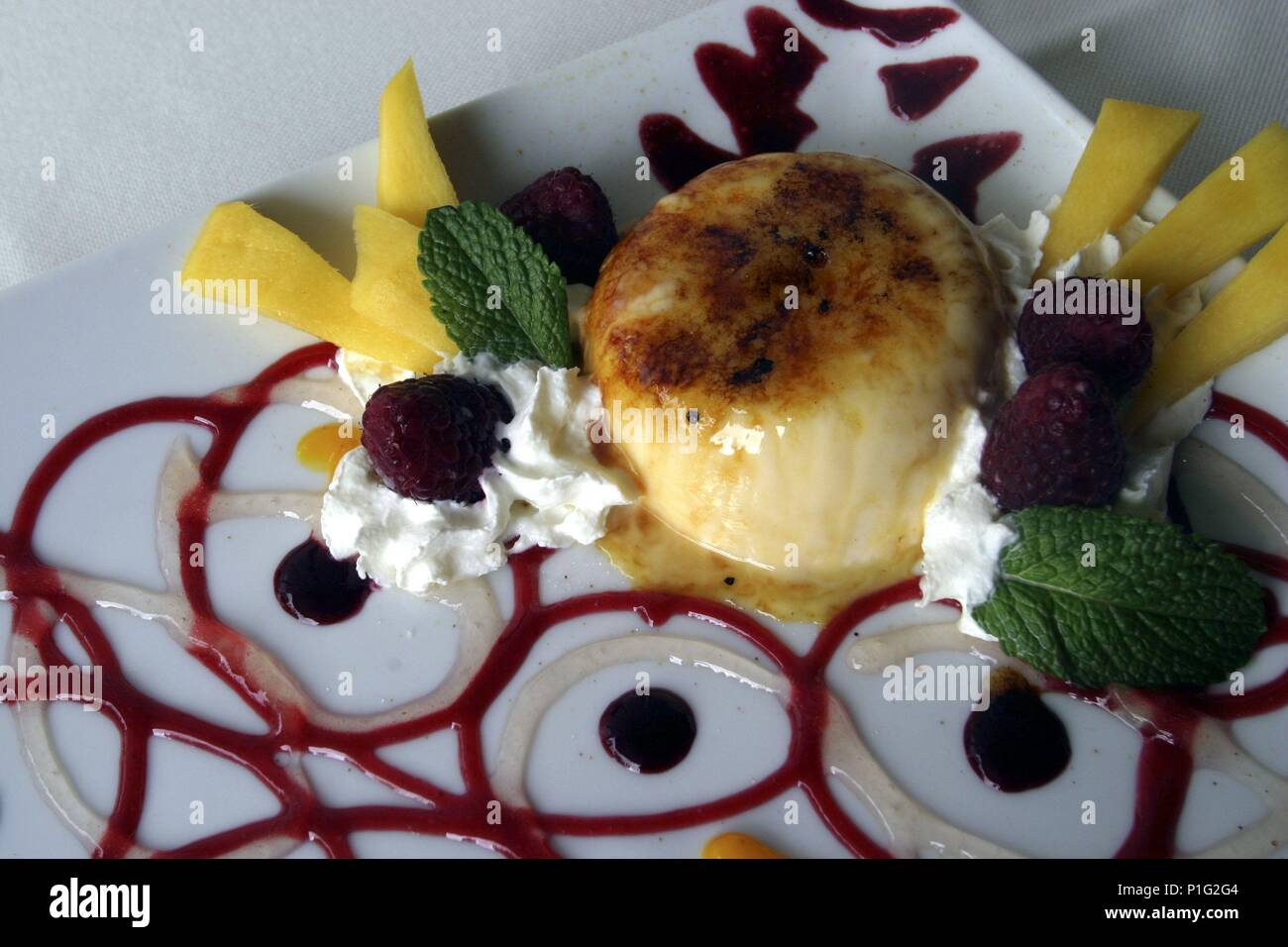 Fuenmayor: Restaurante/Asador' Alameda'; postre de Mousse de queso caramelizado y Salsa frambuesa. Stockfoto