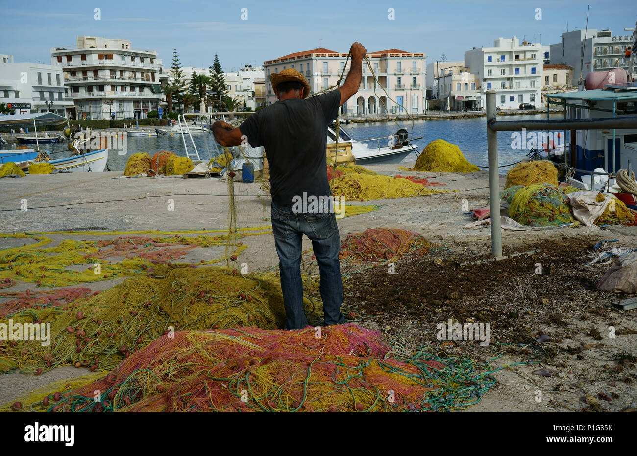Fischer seine Netze Reinigung am Dock in Tinos, Kykladen, Griechenland Stockfoto