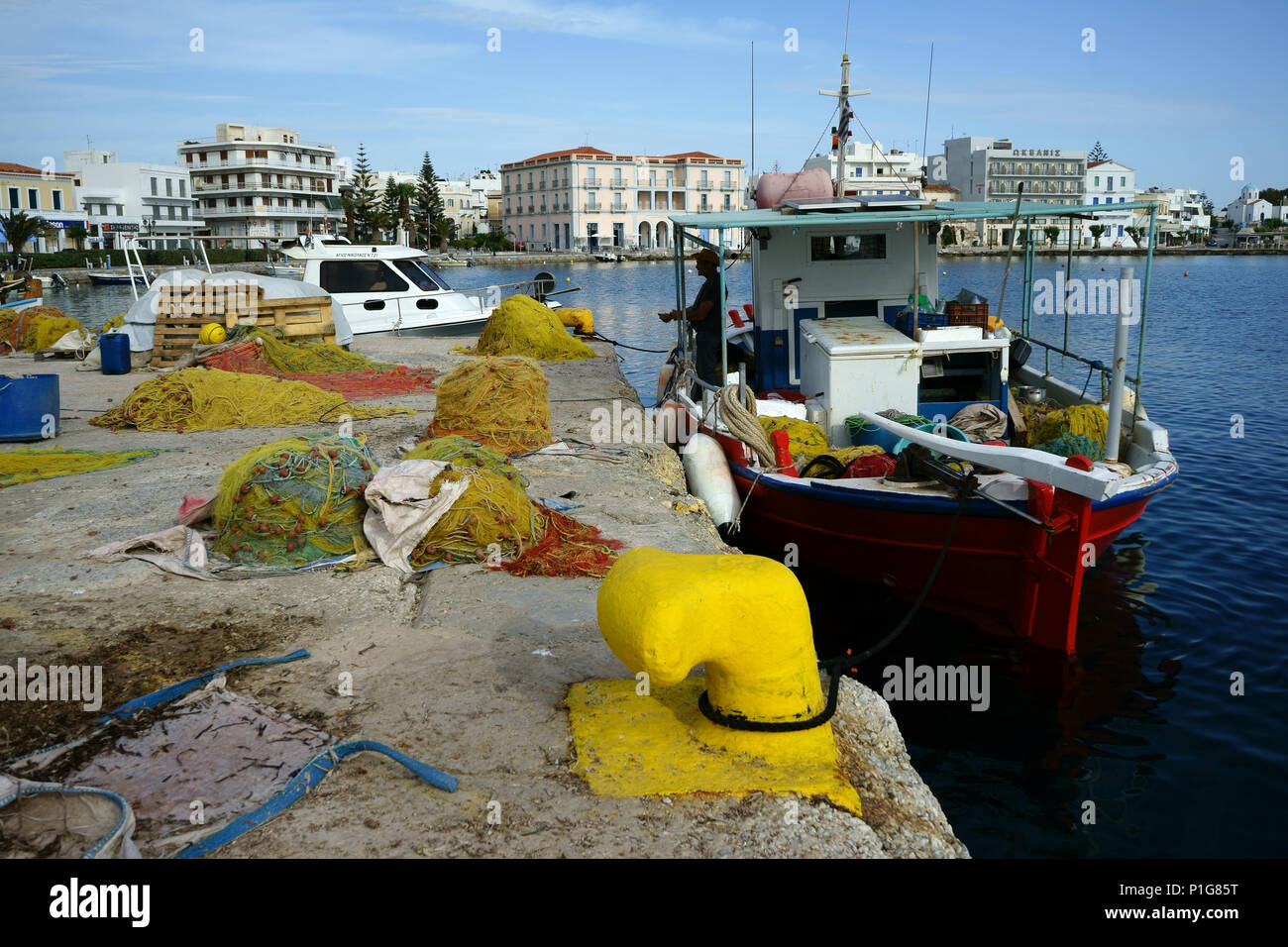 Fischerboote und Netze am Hafen mit Stadt Tinos, Kykladen, Griechenland Stockfoto