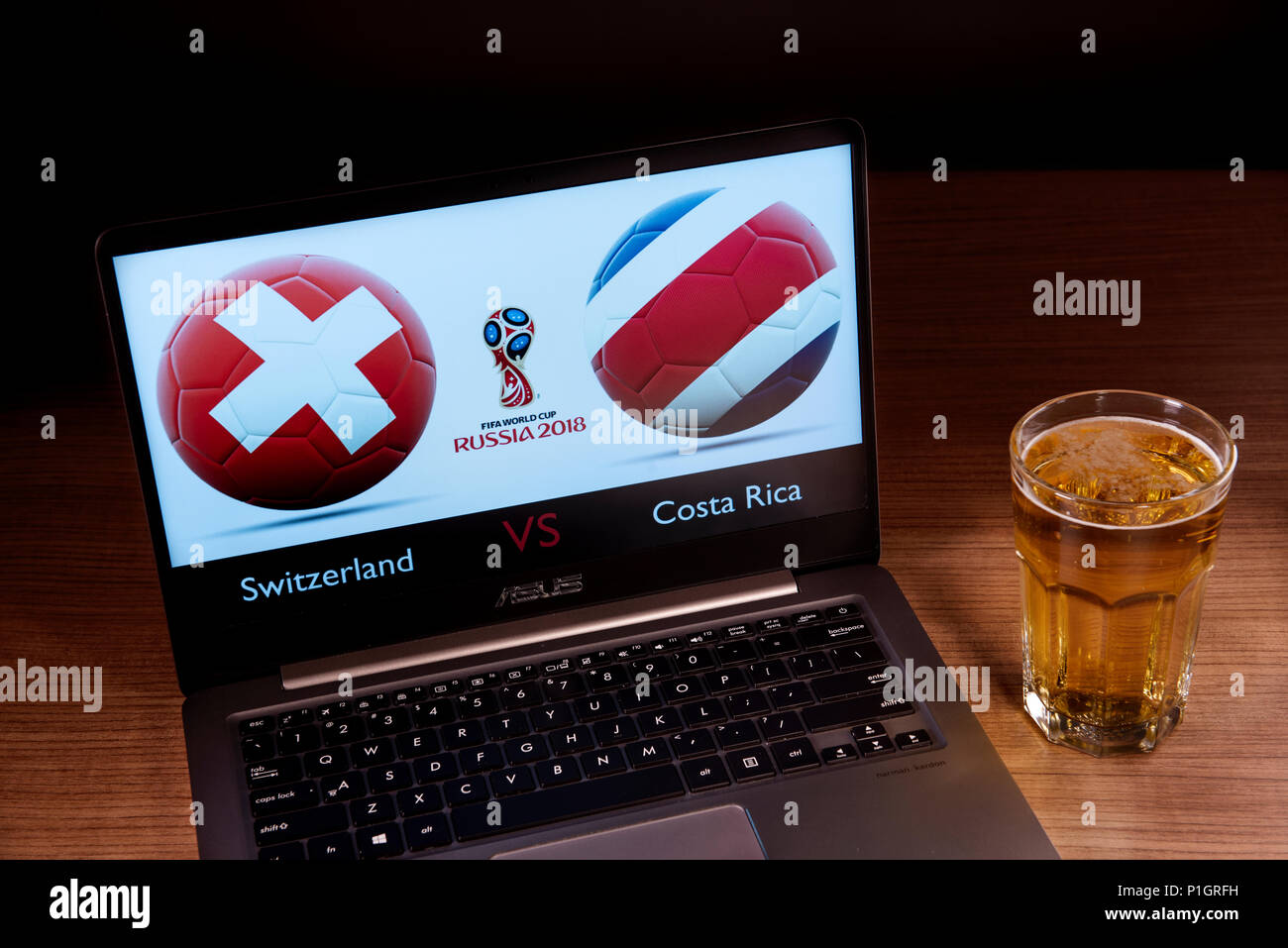 Die Schweizer und Costa Rica Flaggen zusammen gesehen mit der Russischen WM-Logo 2018 angezeigt auf einem Laptop neben einem Glas Bier. Dieses Spiel gehört zu den ersten Match up aus der Gruppe E und wird in Moskau, Russland gespielt werden. Stockfoto