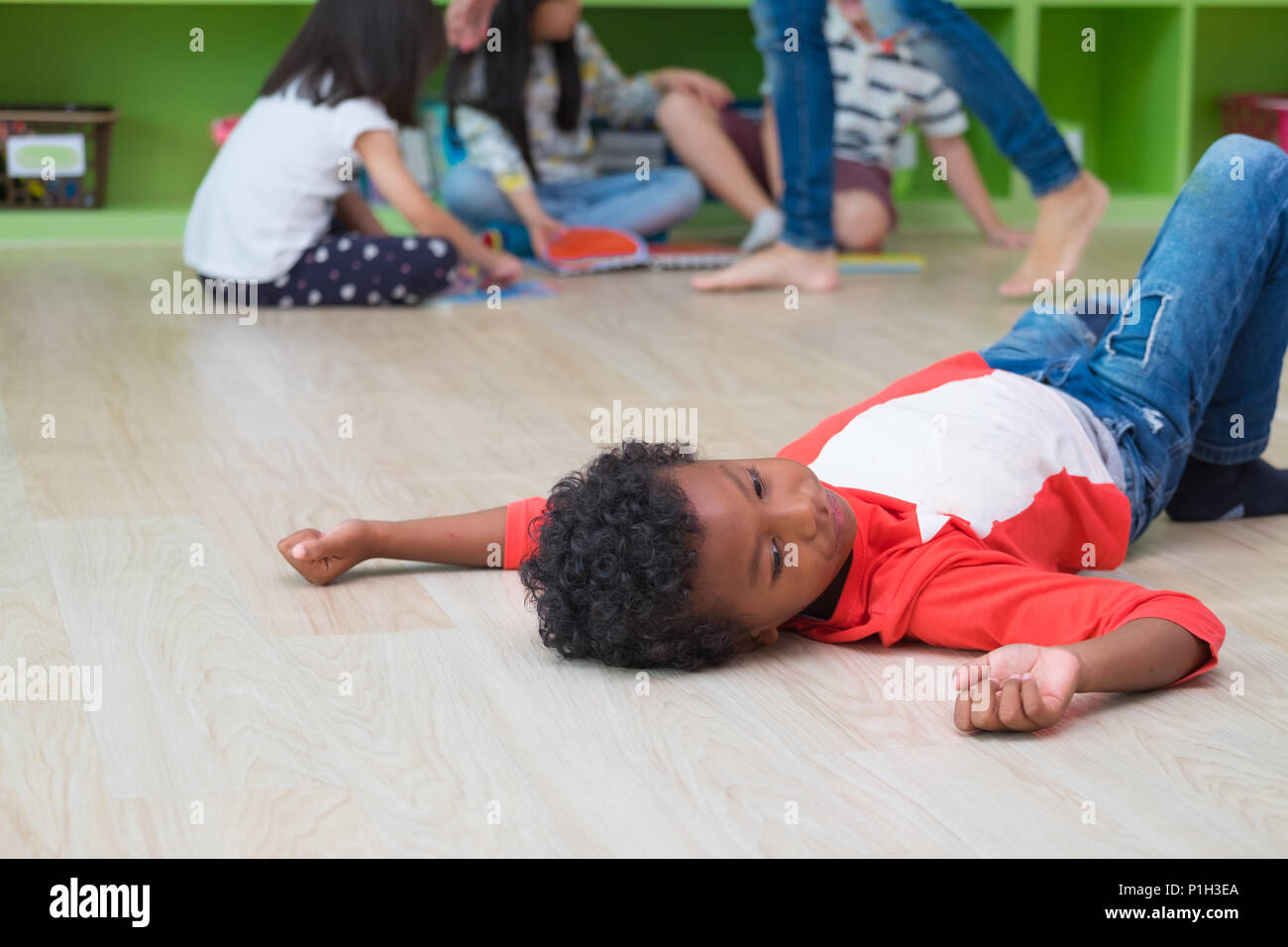 African American kid mit Einsamkeit emotion getrennt von einer Gruppe von Freunden im Klassenzimmer im Kindergarten Vorschule. Mobbing Depressionen Konzept Stockfoto