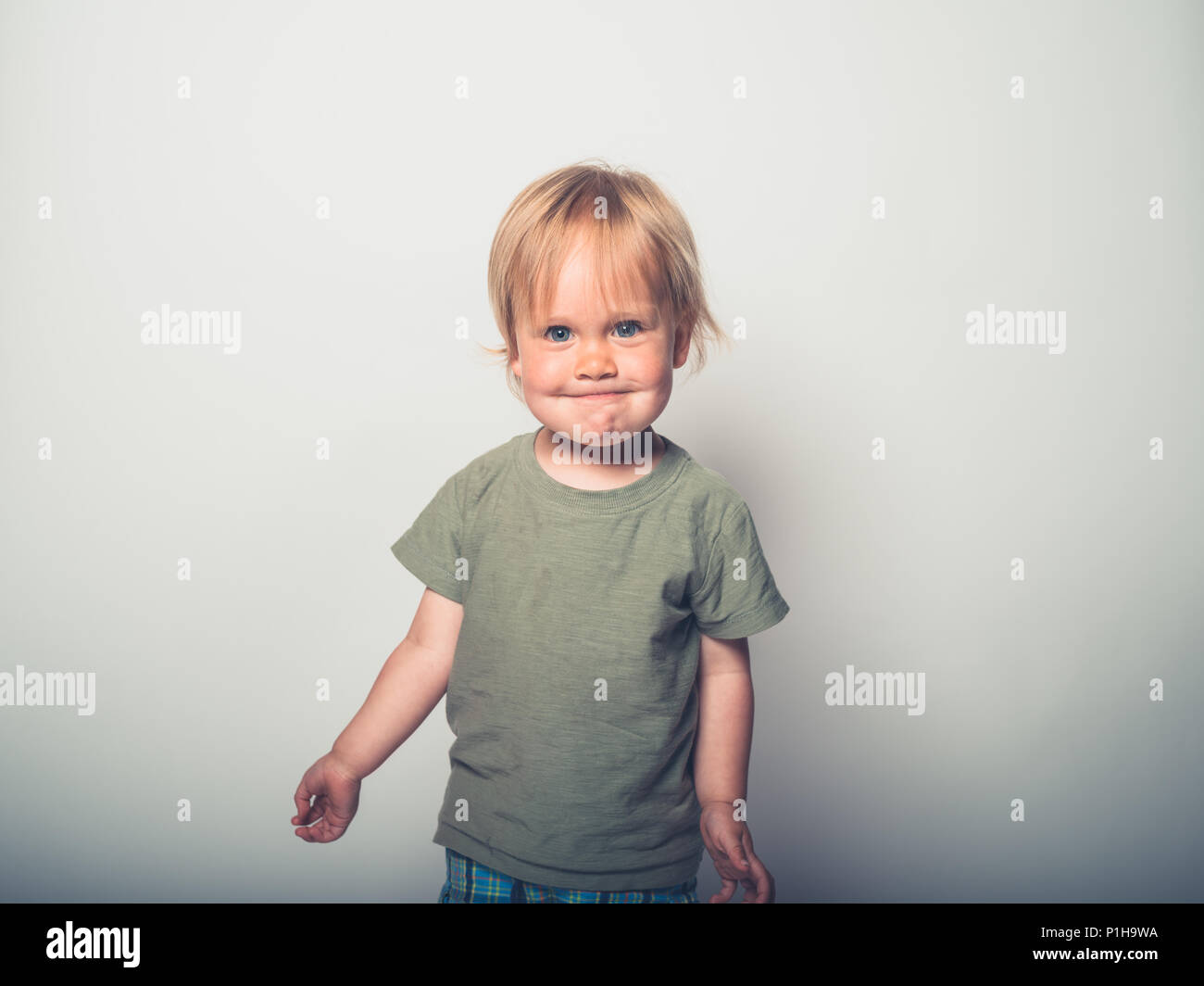 Ein süßes kleines toddler Boy ist ein auf einem weißen Hintergrund darstellen und Grimassen Stockfoto