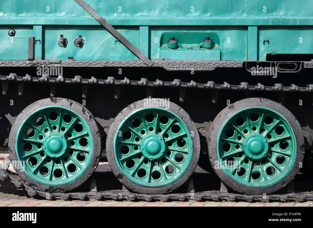 Seitenansicht des Fahrzeugs auf einen Caterpillar Track mit schwarzen Titel und grünen Rädern und einer Seite metall Wand Stockfoto