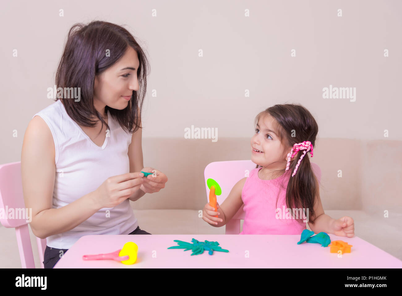 Schönen Mutter und nettes Mädchen spielen zusammen mit Knetmasse, beim Sitzen am Tisch. Stockfoto