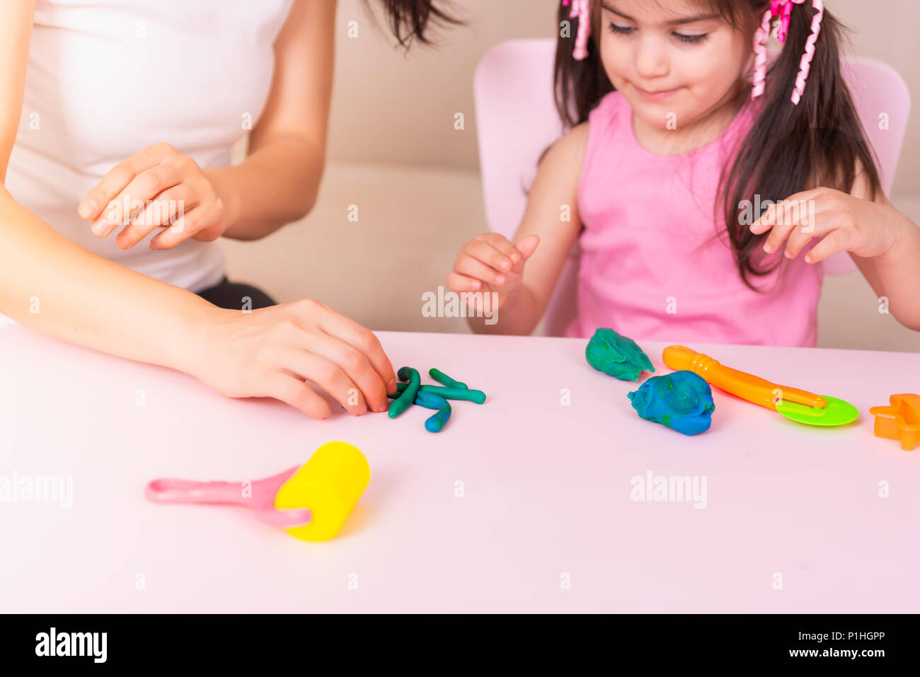 Mutter und nettes Mädchen spielen zusammen mit Knetmasse, beim Sitzen am Tisch. selektive Fokus und kleine Tiefenschärfe. Stockfoto
