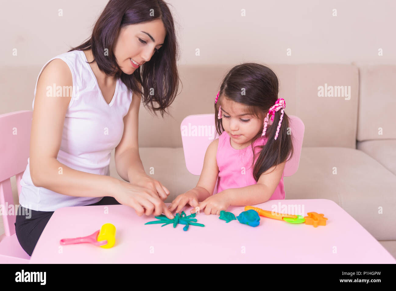 Gerne schönen Mutter und nettes Mädchen spielen zusammen mit Knetmasse, beim Sitzen am Tisch. Stockfoto