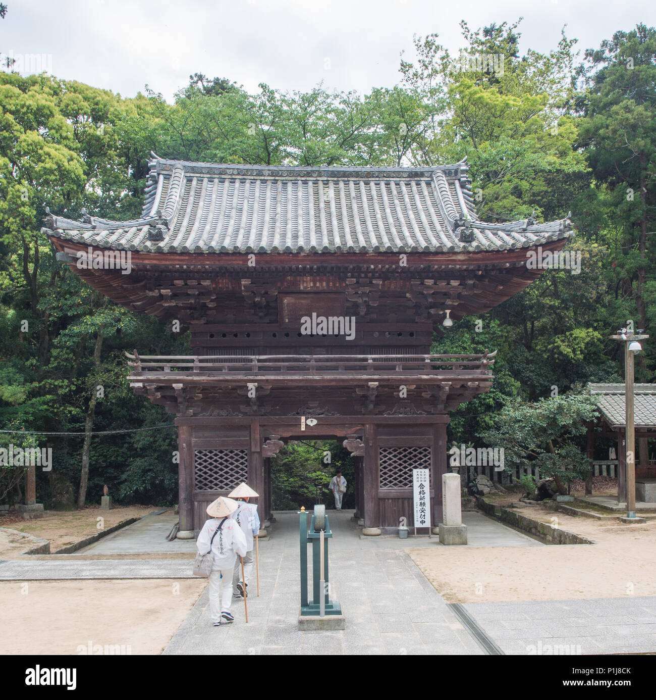 Zwei henro pigrims verlassen, ein ankommen, die Gate House, Taisanji Tempel 52, Shikoku 88 Tempel Wallfahrt, Ehime, Japan. Stockfoto