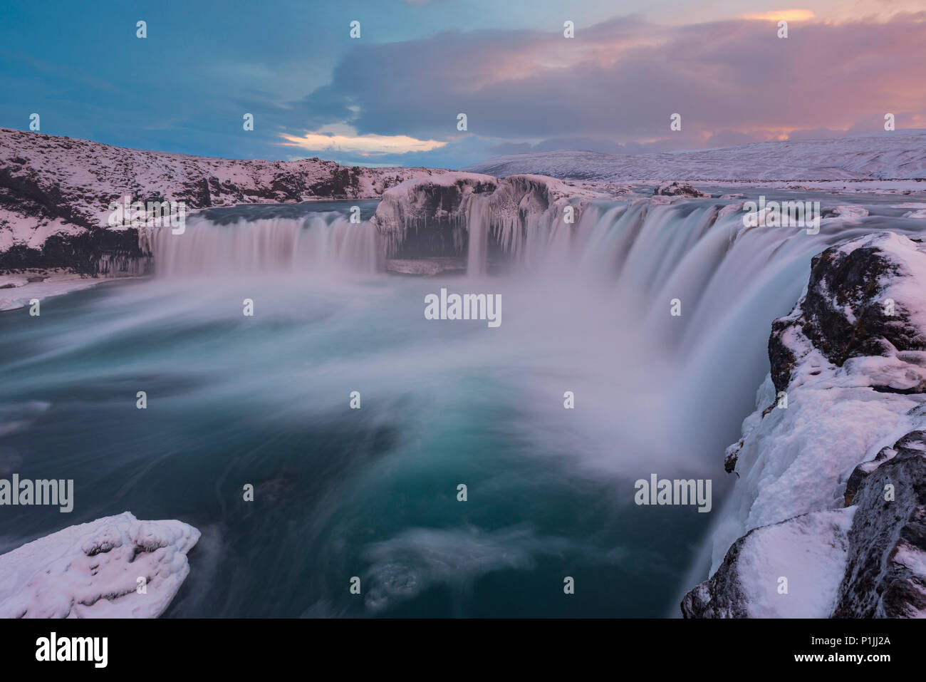 Abendlicht über Godafoss Wasserfall bei Eis und Schnee im Winter, Highlands, Island Stockfoto