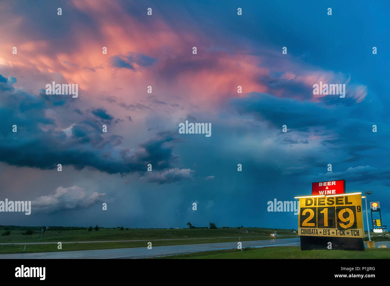 Gewitter (Cumulonimbus capillatus Mammatus) nach Sonnenuntergang während der Blauen Stunde mit Tankstelle in Texas, USA Stockfoto