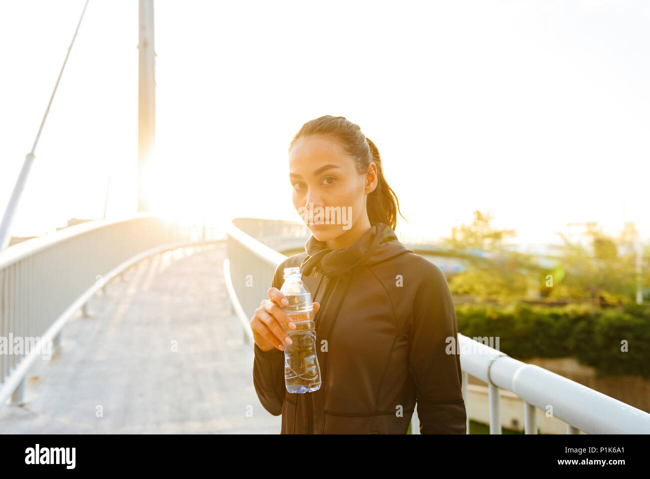 Bild von erstaunlich schöne junge asiatische Sportarten Frau trinkt Wasser draußen. Stockfoto