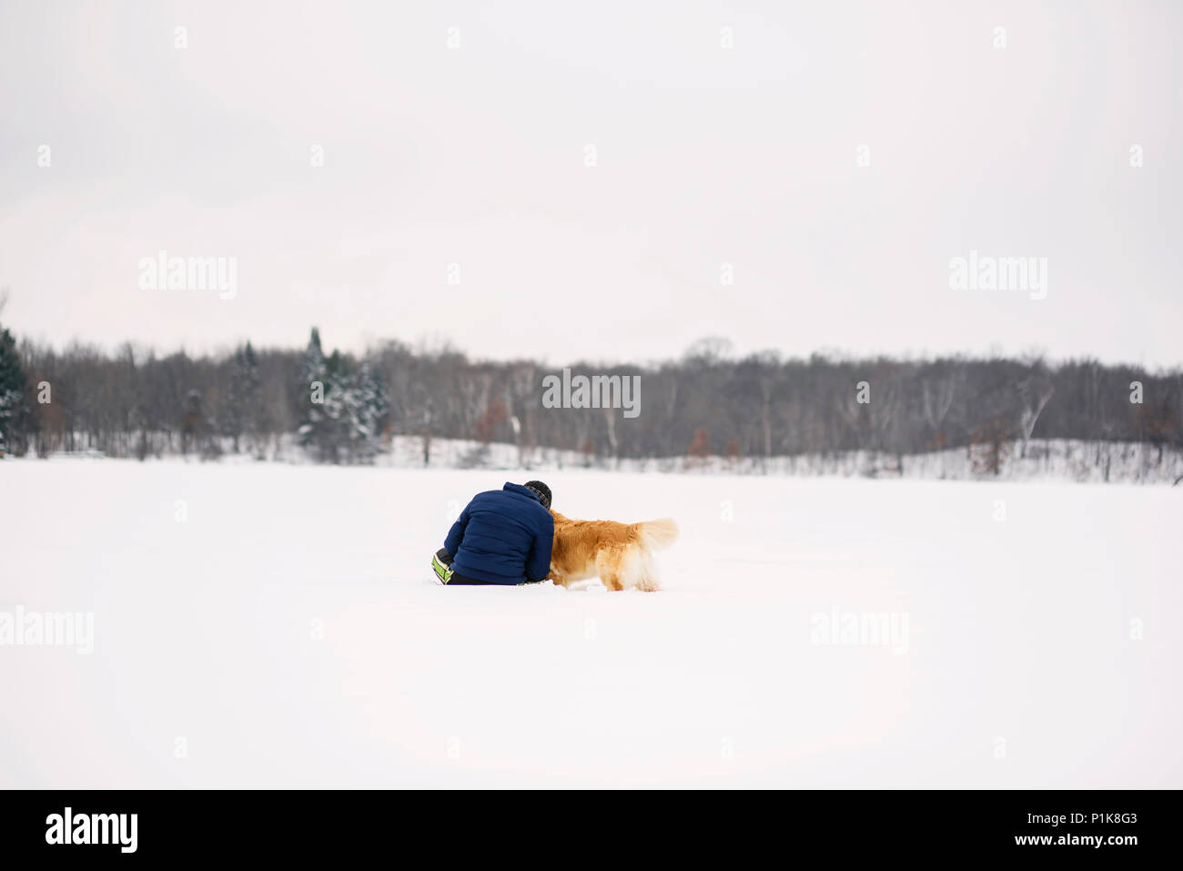 Mann sitzt im Schnee mit seinem Golden Retriever Hund Stockfoto