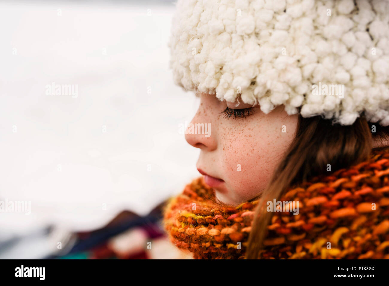 Portrait von ein stehendes Mädchen im Schnee trägt dann eine Wollmütze Stockfoto
