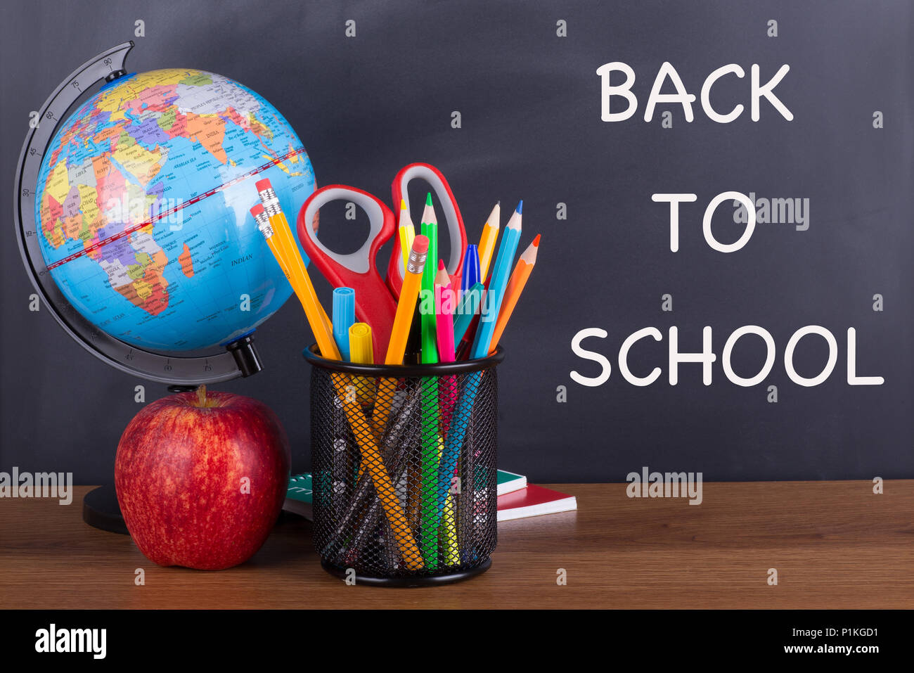 "Zurück zur Schule" Text auf einer Schiefertafel mit Schule Zubehör auf einer hölzernen Desktop geschrieben Stockfoto